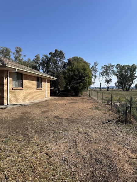 A cleared area of dry ground along the side of a brick house