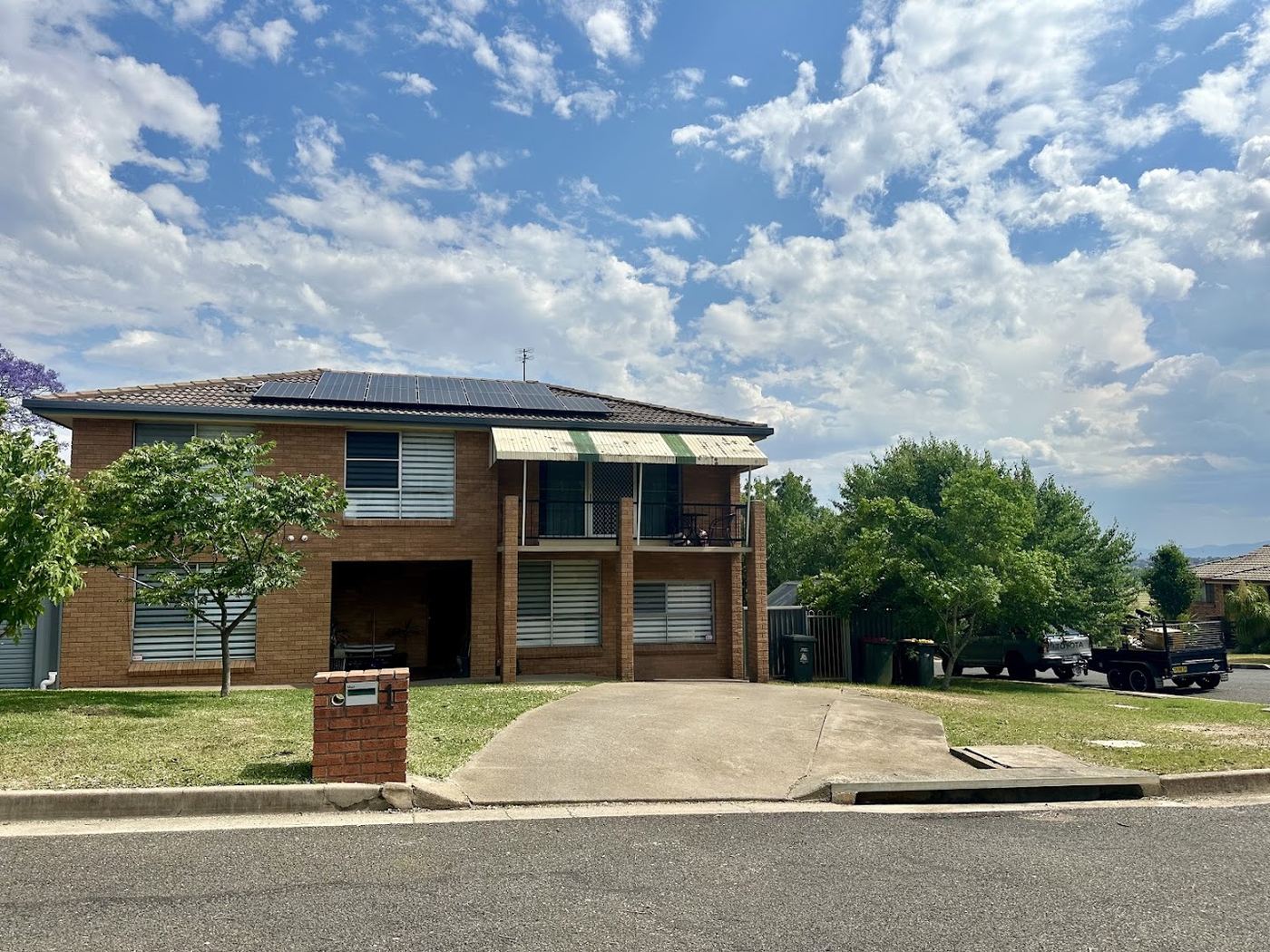 A brick home with a wide concrete driveway and open lawn at the front